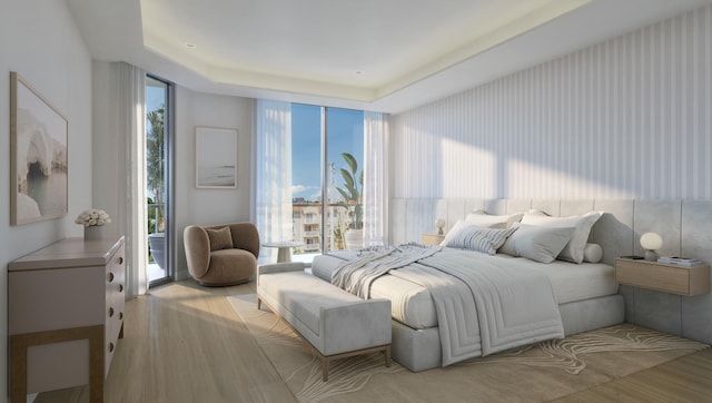 bedroom featuring multiple windows, a raised ceiling, light wood-type flooring, and a wall of windows