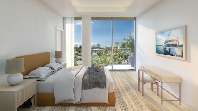 bedroom with floor to ceiling windows, a raised ceiling, and light wood-type flooring