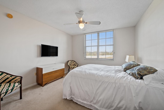 bedroom featuring ceiling fan, light colored carpet, and a textured ceiling