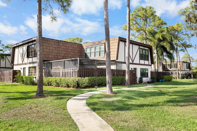 back of property with fence, mansard roof, a lawn, and stucco siding