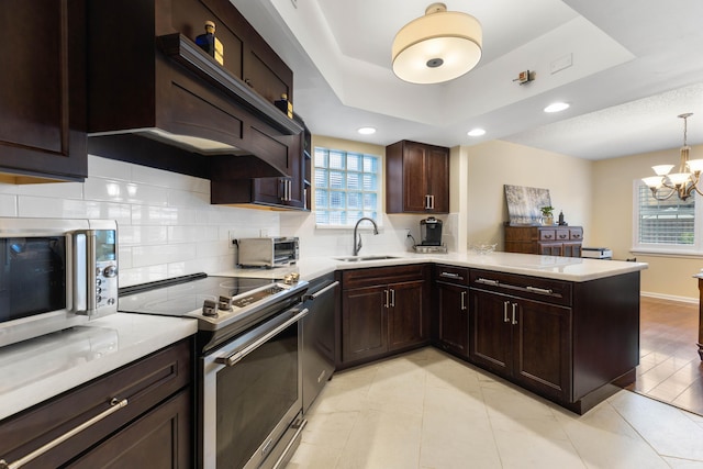 kitchen featuring a peninsula, light countertops, appliances with stainless steel finishes, and a tray ceiling