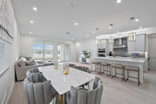 dining space featuring light wood finished floors, a toaster, baseboards, and recessed lighting