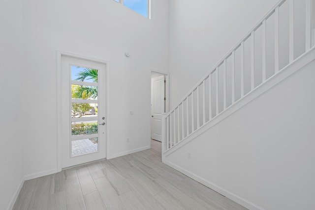 entrance foyer with a towering ceiling and light wood-type flooring