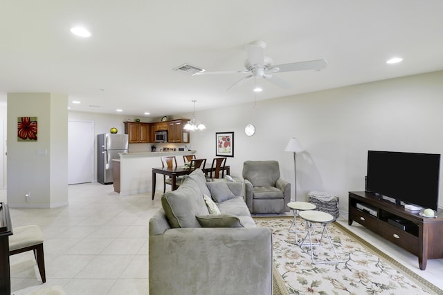 tiled living room with ceiling fan with notable chandelier