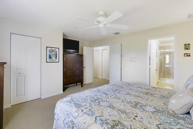 carpeted bedroom with ceiling fan, ensuite bathroom, and two closets