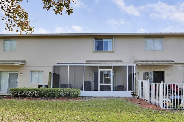 rear view of house featuring a yard and a sunroom