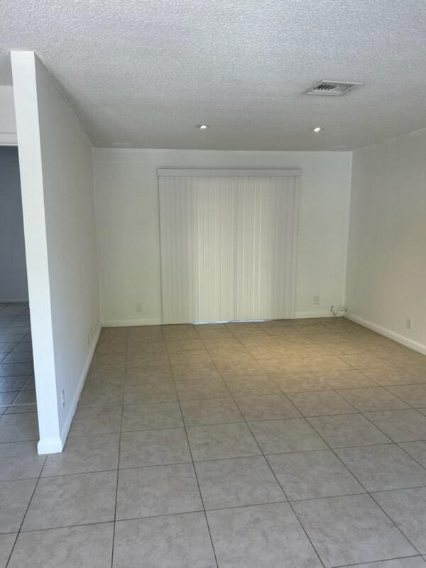 tiled empty room with a textured ceiling