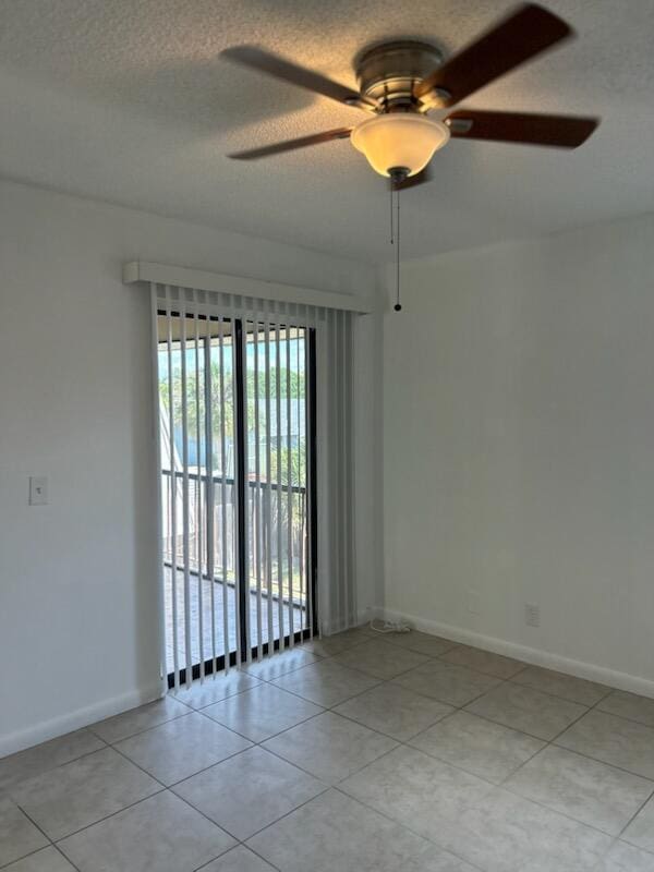 tiled empty room featuring ceiling fan and a textured ceiling