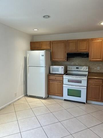 kitchen with light tile patterned flooring, white appliances, and backsplash