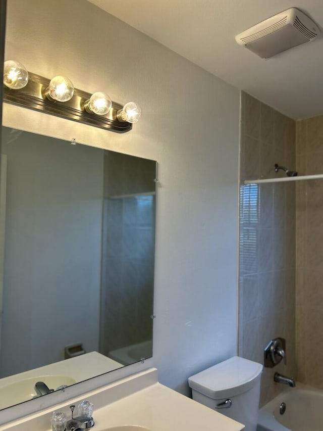 full bathroom featuring vanity, tiled shower / bath combo, and toilet