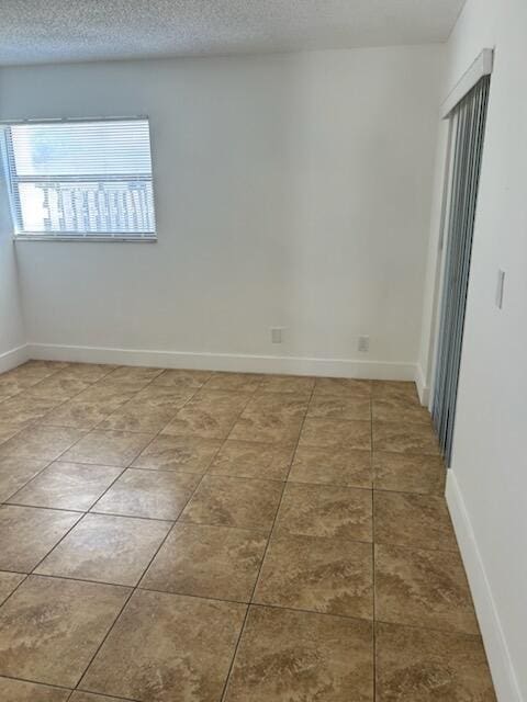 unfurnished room featuring tile patterned flooring and a textured ceiling