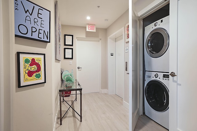 clothes washing area with stacked washing maching and dryer and light hardwood / wood-style flooring