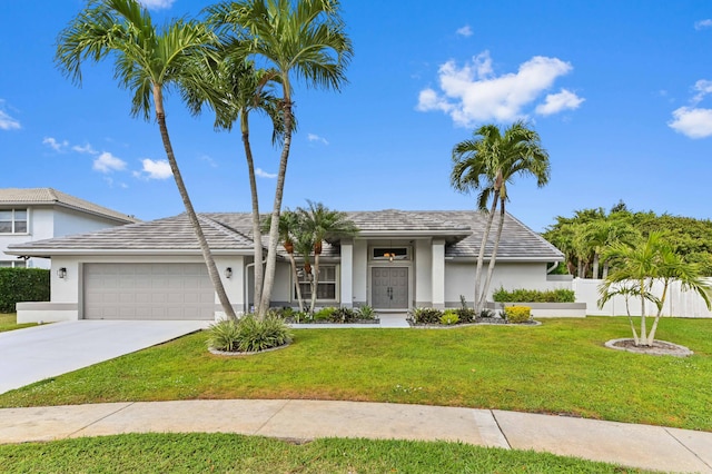 view of front of home with stucco siding, a front yard, fence, a garage, and driveway