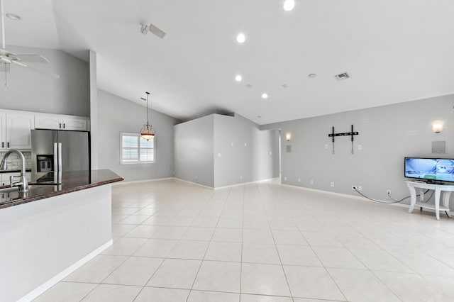unfurnished living room with vaulted ceiling, visible vents, light tile patterned floors, a sink, and ceiling fan