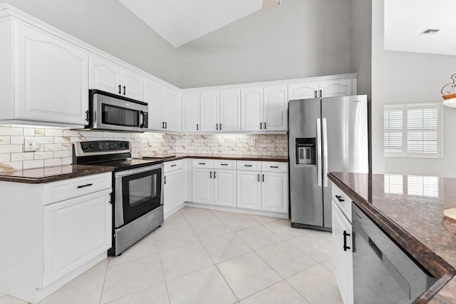 kitchen with stainless steel appliances, a high ceiling, decorative backsplash, and white cabinetry