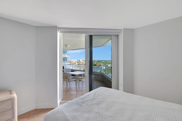 bedroom featuring a water view, light tile patterned floors, heating unit, and access to outside