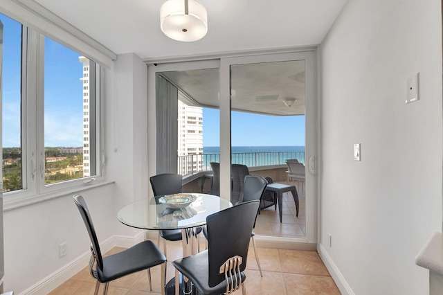 dining room featuring a water view, light tile patterned flooring, and a wealth of natural light