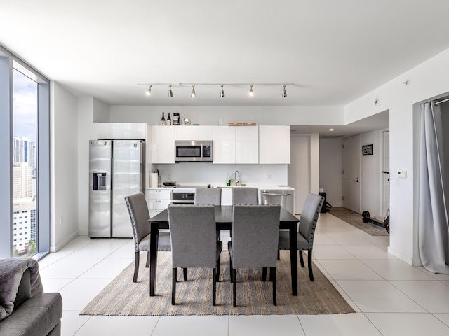 tiled dining space featuring floor to ceiling windows and rail lighting