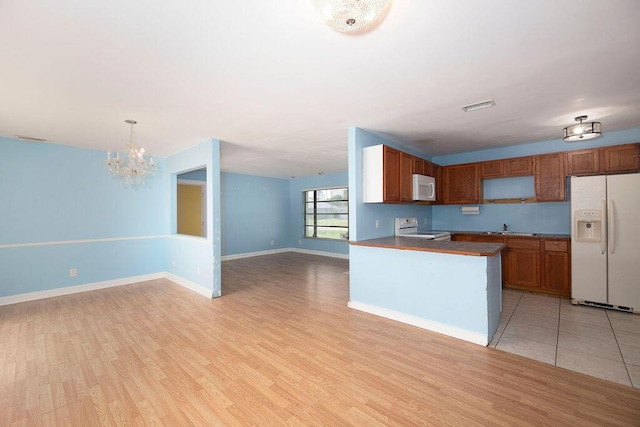 kitchen with light hardwood / wood-style floors, sink, white appliances, and decorative light fixtures