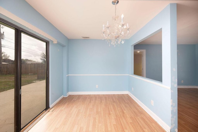 empty room featuring an inviting chandelier and light wood-type flooring