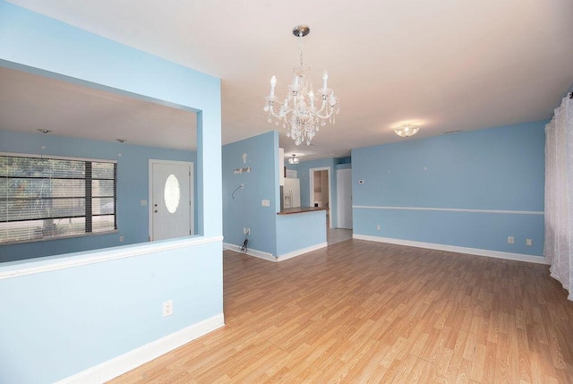 unfurnished living room featuring a chandelier and light wood-type flooring