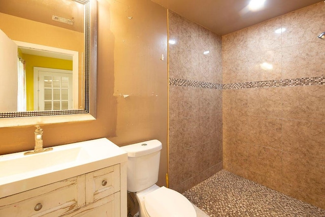 bathroom with vanity, toilet, and a tile shower