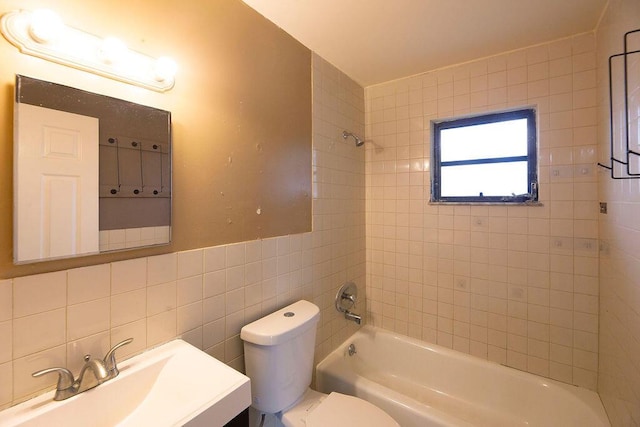 full bathroom featuring tiled shower / bath combo, vanity, tile walls, and toilet