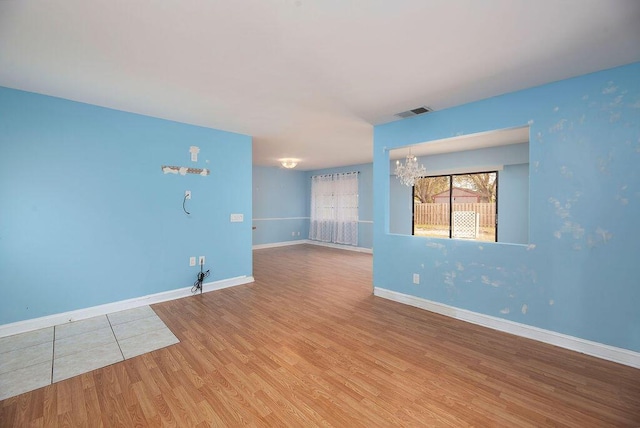 empty room featuring wood-type flooring and a chandelier