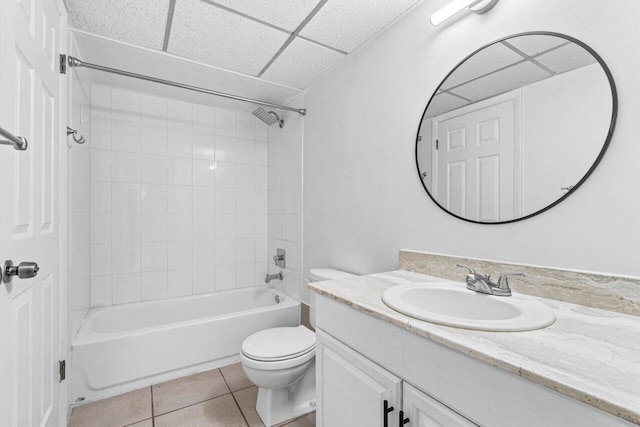 full bathroom featuring tiled shower / bath, vanity, toilet, a drop ceiling, and tile patterned floors