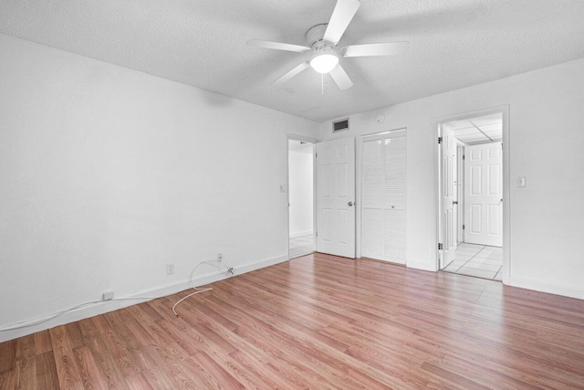 unfurnished bedroom with ceiling fan, light hardwood / wood-style flooring, and a textured ceiling