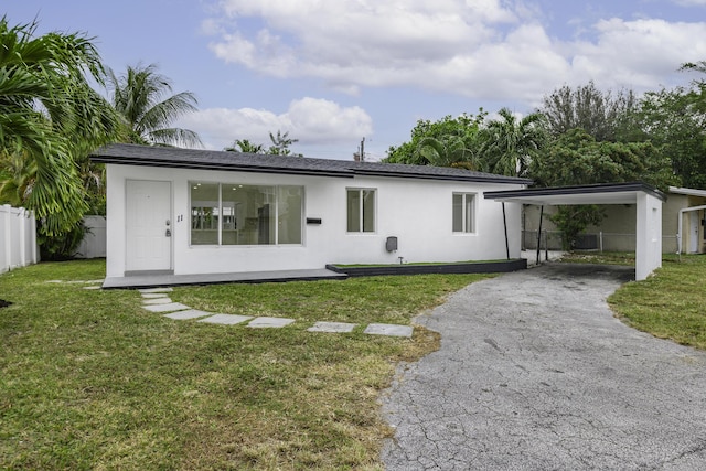 rear view of property with a carport and a lawn