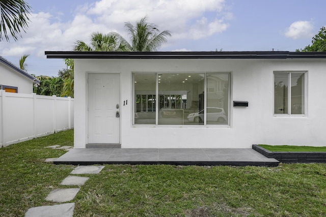 doorway to property with a patio area and a lawn