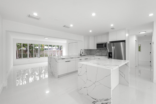 kitchen with a kitchen island, white cabinetry, appliances with stainless steel finishes, and backsplash