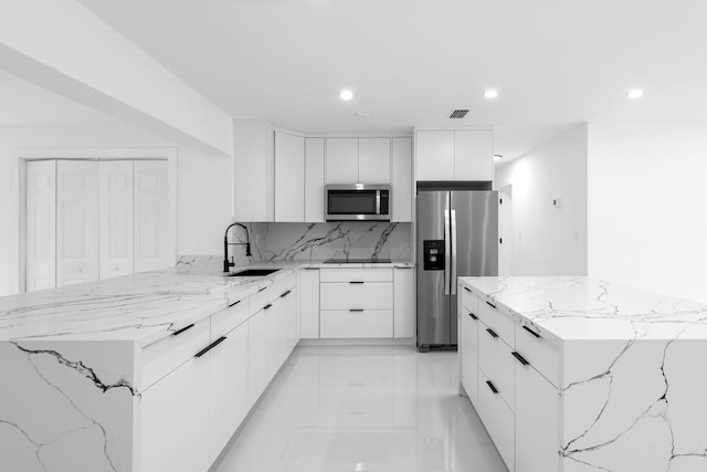 kitchen with sink, tasteful backsplash, a kitchen island, stainless steel appliances, and white cabinets