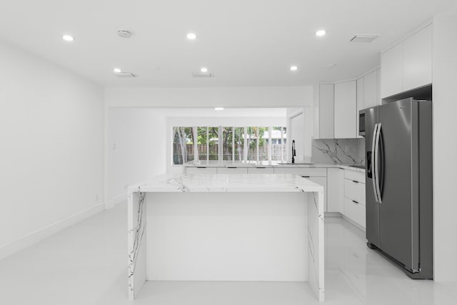 kitchen with stainless steel fridge with ice dispenser, white cabinets, and a kitchen island