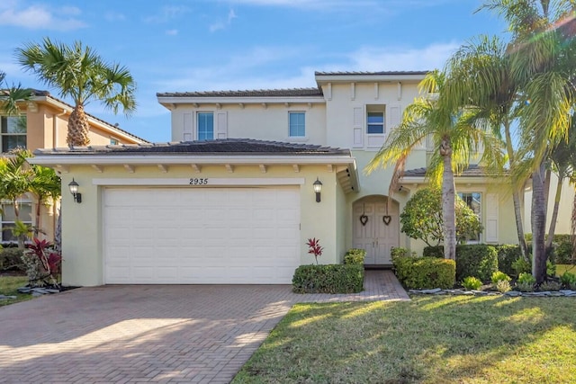 view of front facade featuring a garage, a front yard, decorative driveway, and stucco siding