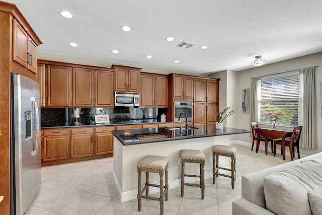 kitchen with stainless steel appliances, a kitchen breakfast bar, sink, and a center island with sink