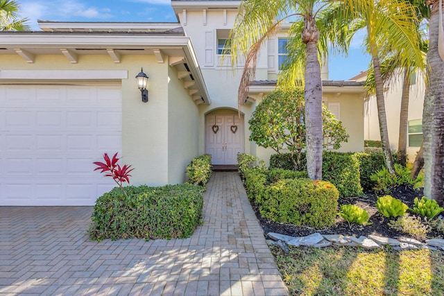 view of exterior entry featuring an attached garage and stucco siding