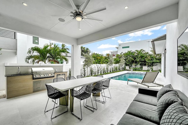 view of patio / terrace with exterior kitchen, an outdoor wet bar, ceiling fan, grilling area, and a fenced in pool