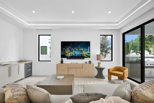 living room featuring a raised ceiling, wet bar, and beverage cooler