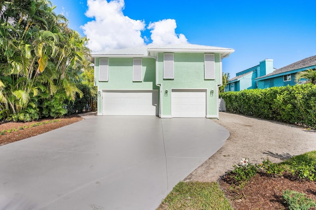 view of front facade with a garage, concrete driveway, and stucco siding