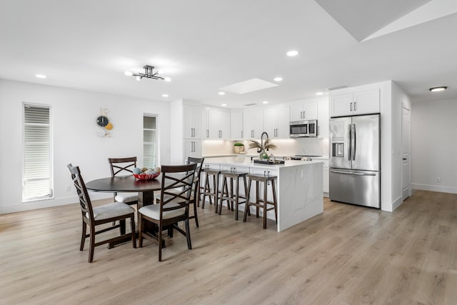 dining area featuring light wood finished floors, a skylight, baseboards, visible vents, and recessed lighting