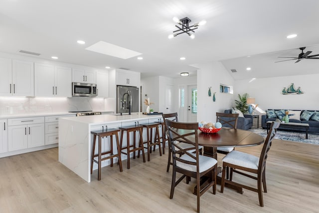 dining space featuring light wood-style flooring, lofted ceiling with skylight, visible vents, and recessed lighting