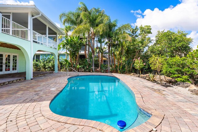 outdoor pool with french doors and a patio area