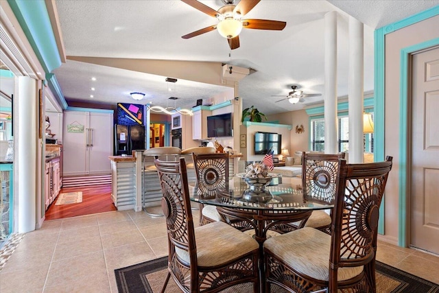 dining space with vaulted ceiling, light tile patterned floors, a ceiling fan, and ornate columns