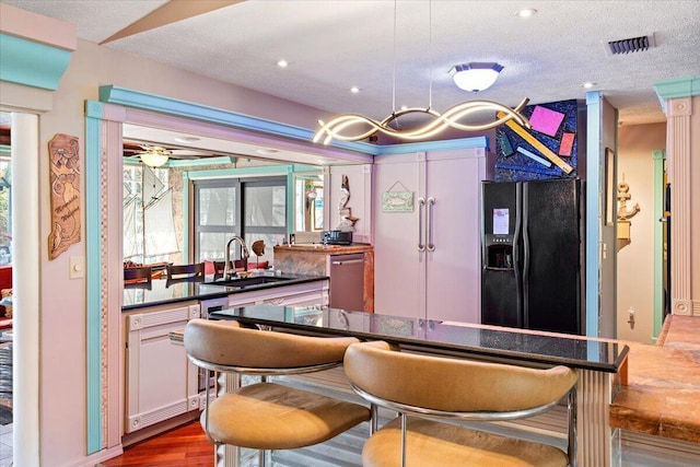 bar featuring visible vents, a sink, a textured ceiling, dishwasher, and black refrigerator with ice dispenser