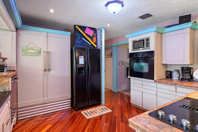 kitchen featuring visible vents, black appliances, dark wood-style floors, white cabinets, and a textured ceiling