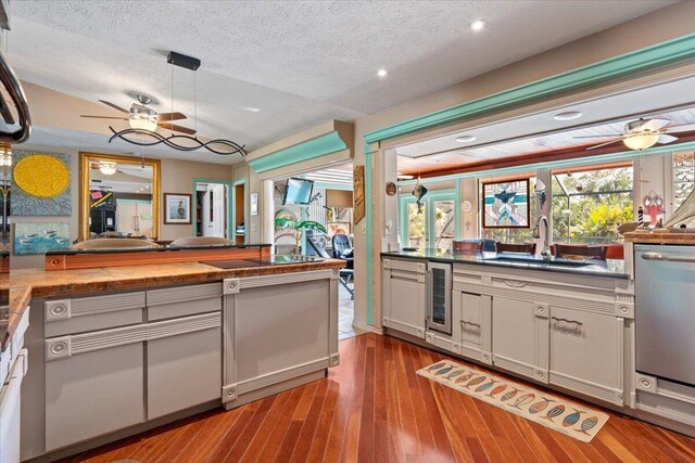 kitchen with sink, ceiling fan, dishwasher, a textured ceiling, and light wood-type flooring