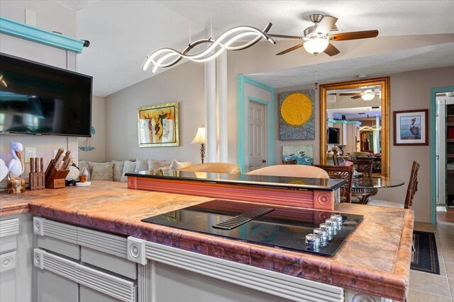 kitchen featuring black electric cooktop, light tile patterned floors, vaulted ceiling, and ceiling fan