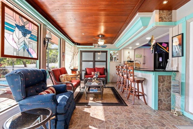 interior space featuring wooden ceiling, stone floors, and a ceiling fan